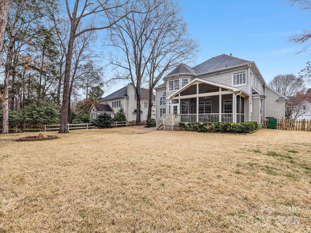 rear view of property with a yard, fence private yard, and a sunroom