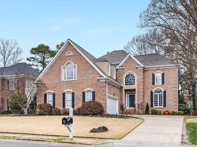 view of front facade with a front lawn, roof with shingles, concrete driveway, a garage, and brick siding