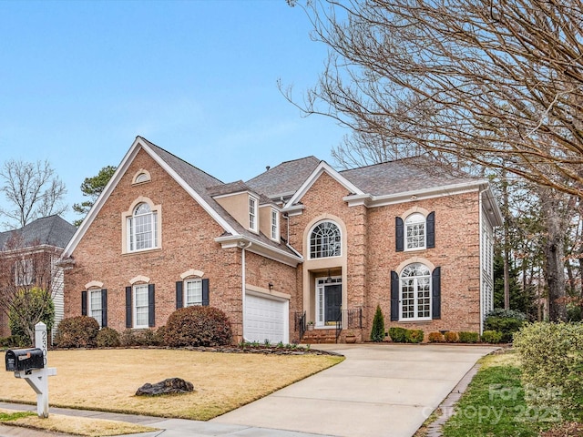 view of front of property with a shingled roof, concrete driveway, a front lawn, a garage, and brick siding