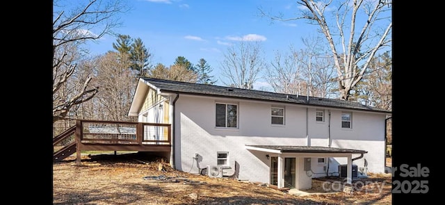 rear view of house with brick siding, a deck, and central AC unit