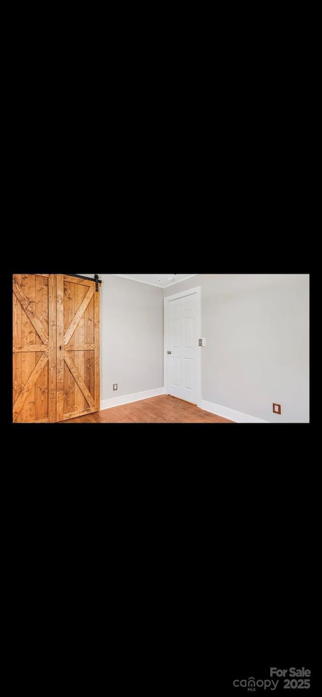 unfurnished room with a barn door and baseboards