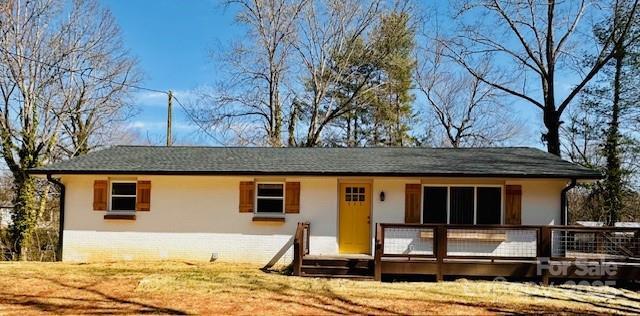 rear view of property with a deck, a yard, and stucco siding