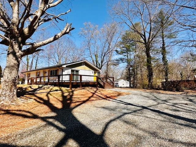 view of property exterior with driveway and a wooden deck