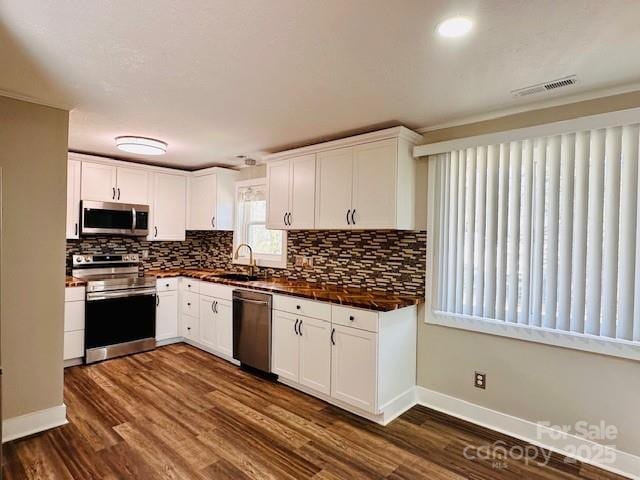 kitchen with dark countertops, visible vents, white cabinetry, and stainless steel appliances