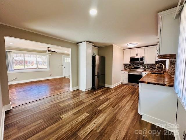 kitchen featuring a sink, tasteful backsplash, appliances with stainless steel finishes, white cabinets, and butcher block counters