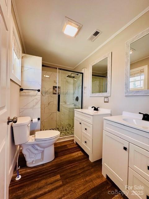 full bathroom featuring wood finished floors, a stall shower, a sink, ornamental molding, and toilet