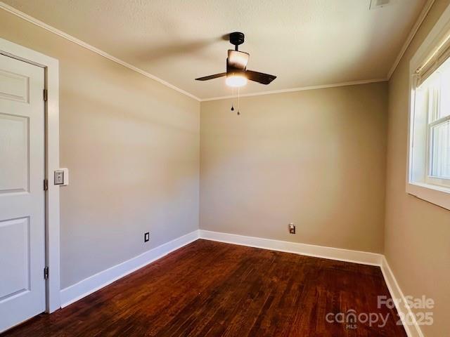 spare room featuring baseboards, wood finished floors, and crown molding