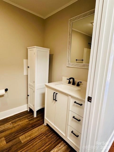 bathroom with vanity, crown molding, wood finished floors, and baseboards