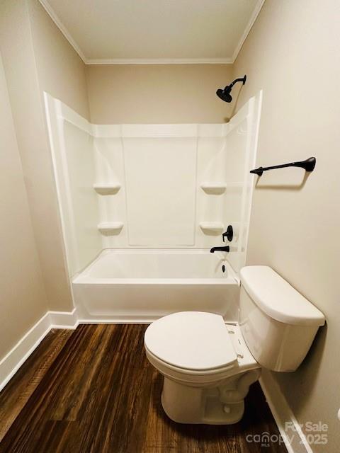 bathroom featuring shower / bathing tub combination, toilet, wood finished floors, and ornamental molding