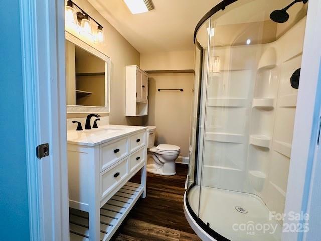 full bath featuring wood finished floors, toilet, a stall shower, and vanity