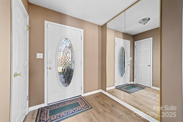 entrance foyer with baseboards and wood finished floors