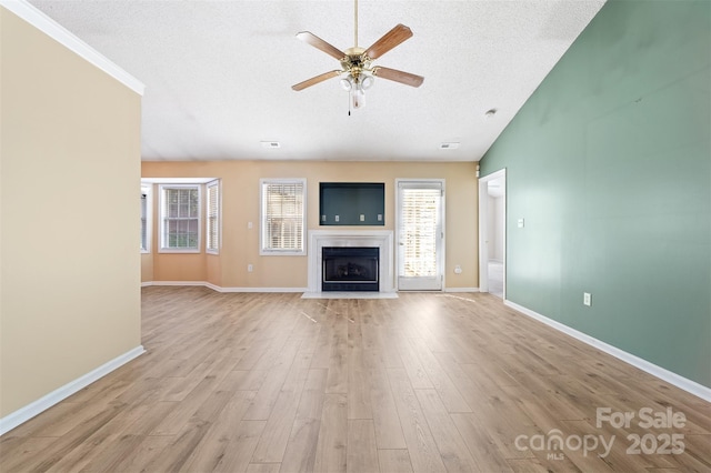 unfurnished living room featuring baseboards, ceiling fan, a textured ceiling, light wood-style floors, and a fireplace