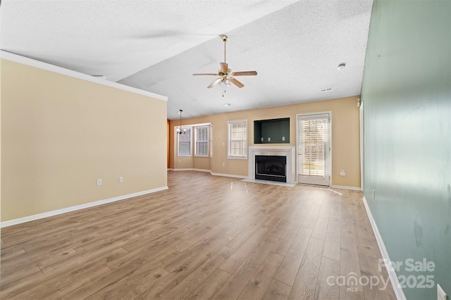 unfurnished living room with light wood finished floors, a ceiling fan, a fireplace with flush hearth, vaulted ceiling, and a textured ceiling