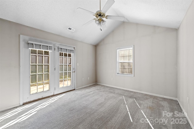 spare room with carpet floors, visible vents, a ceiling fan, vaulted ceiling, and a textured ceiling