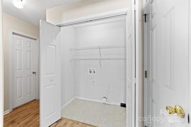 clothes washing area featuring laundry area, baseboards, a textured ceiling, light wood-style floors, and washer hookup