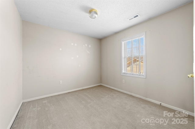 empty room with a textured ceiling, carpet flooring, visible vents, and baseboards