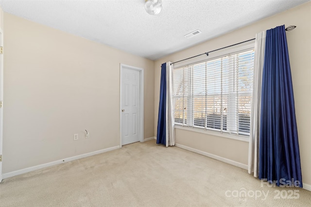 carpeted spare room featuring visible vents, a textured ceiling, and baseboards