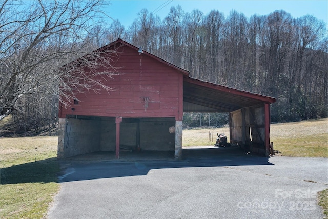 garage with driveway and a wooded view