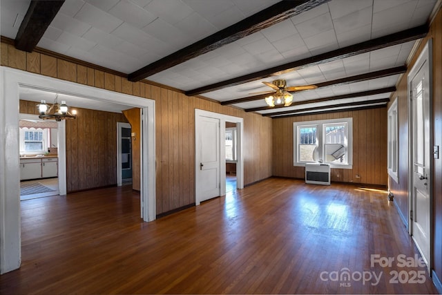 unfurnished living room featuring radiator heating unit, ceiling fan with notable chandelier, dark wood-style flooring, and beamed ceiling