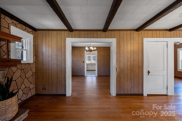 interior space with a chandelier, beamed ceiling, wood finished floors, and baseboards