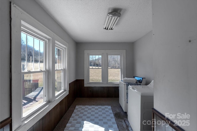 washroom featuring laundry area, wainscoting, a textured ceiling, wood walls, and washing machine and dryer