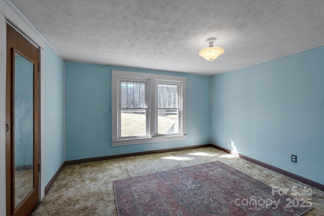 empty room with baseboards, a textured ceiling, and carpet flooring