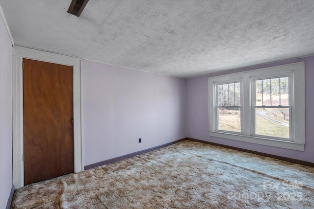 empty room featuring visible vents, carpet flooring, a textured ceiling, and baseboards