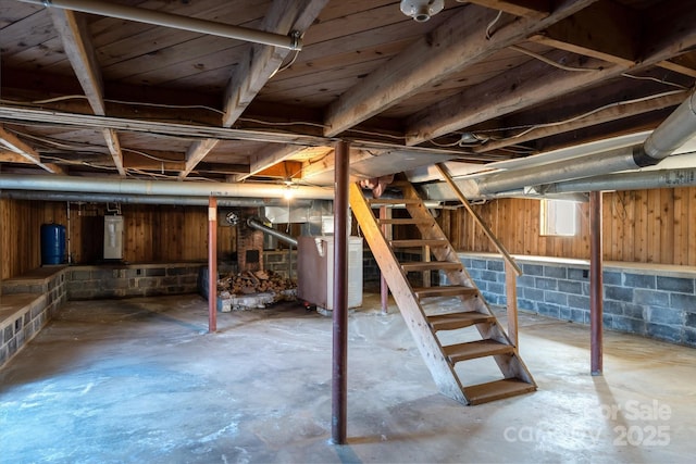 unfinished basement featuring stairs and water heater