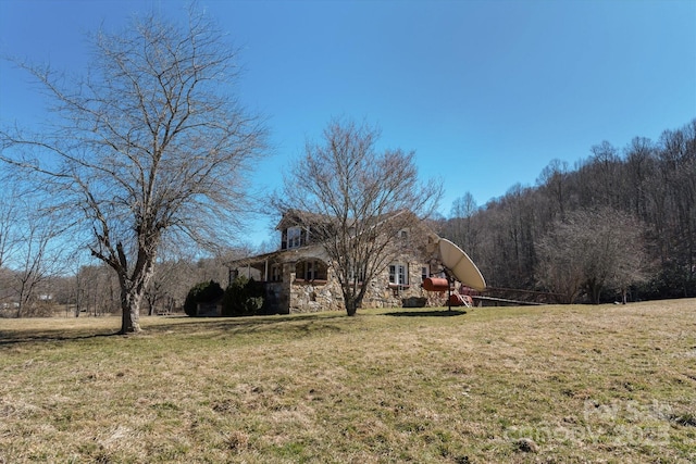 exterior space featuring stone siding and a lawn