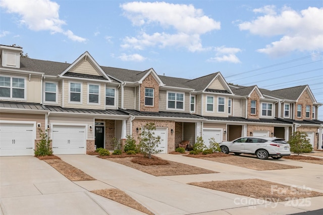 townhome / multi-family property with metal roof, an attached garage, brick siding, driveway, and a standing seam roof