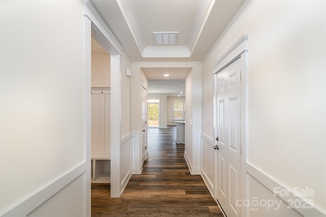 corridor with dark wood-style floors, wainscoting, visible vents, and a decorative wall