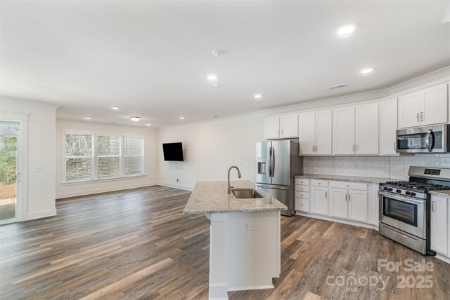 kitchen with white cabinets, decorative backsplash, appliances with stainless steel finishes, wood finished floors, and a sink