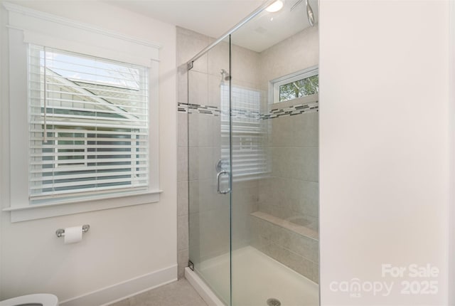 full bath featuring a stall shower, baseboards, and tile patterned floors