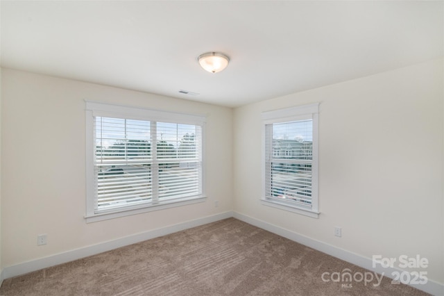 spare room featuring carpet, visible vents, and baseboards