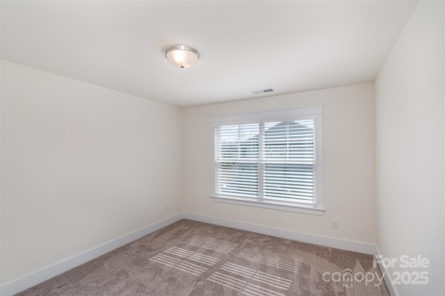 empty room featuring light carpet, visible vents, and baseboards