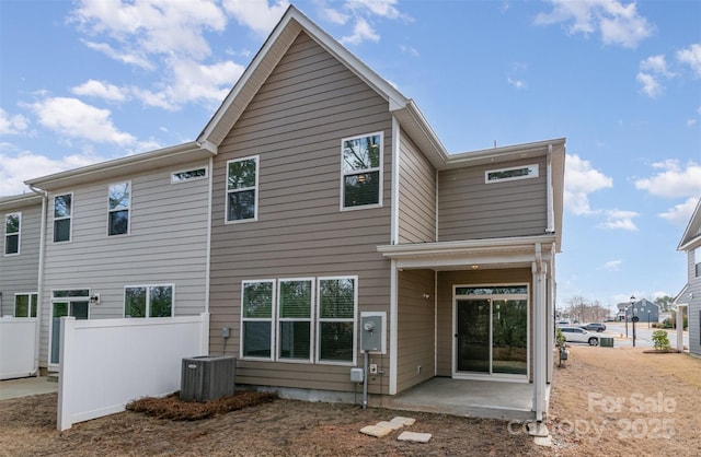 rear view of house with fence, cooling unit, and a patio