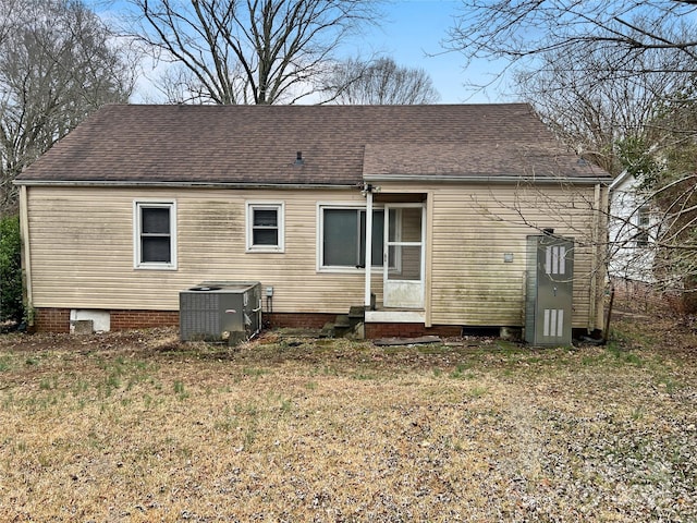 back of house featuring a shingled roof, a lawn, and central AC unit