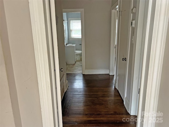 hallway featuring dark wood-style floors and baseboards