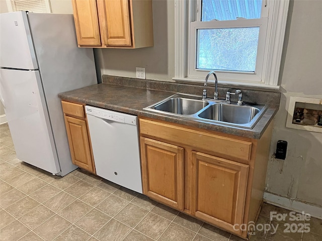 kitchen featuring dark countertops, white appliances, a sink, and light tile patterned flooring