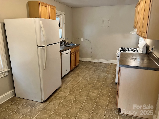 kitchen with dark countertops, white appliances, baseboards, and a sink