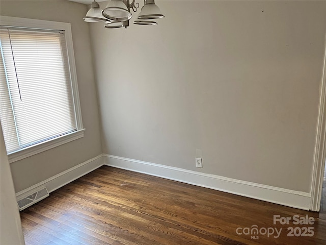 unfurnished room featuring a notable chandelier, baseboards, visible vents, and dark wood-style flooring