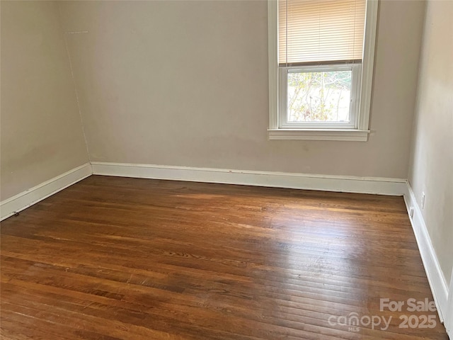 empty room with baseboards and dark wood finished floors