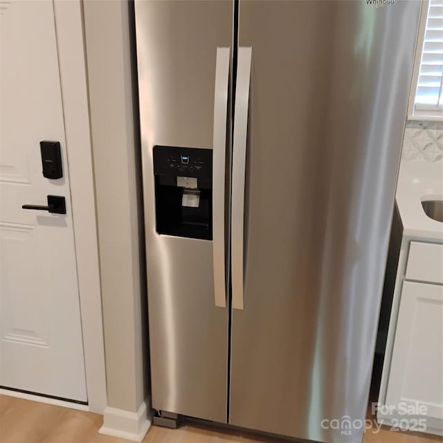 2545 Stockbridge Dr, Charlotte, NC 28210 - kitchen view of stainless steel refrigerator with ice dispenser, white cabinets, light countertops, and baseboards