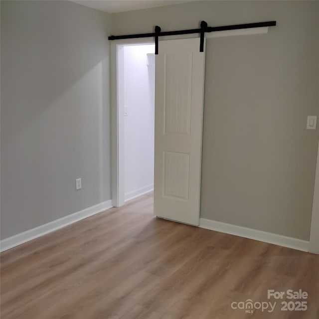 2545 Stockbridge Dr, Charlotte, NC 28210 - empty room with light wood finished floors, baseboards, and a barn door