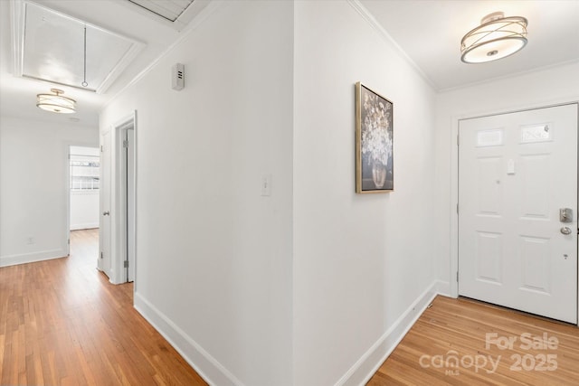 entrance foyer with light wood-type flooring, baseboards, and crown molding