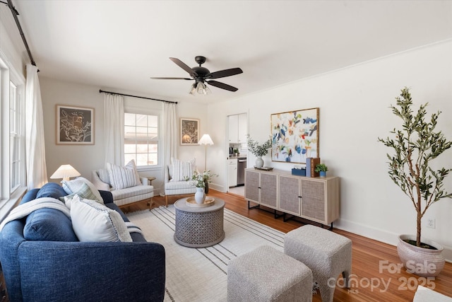 living room featuring baseboards, ceiling fan, and light wood finished floors