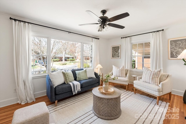 living room featuring ceiling fan, baseboards, a healthy amount of sunlight, and wood finished floors