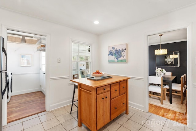 kitchen with a notable chandelier, brown cabinetry, butcher block counters, light tile patterned floors, and hanging light fixtures