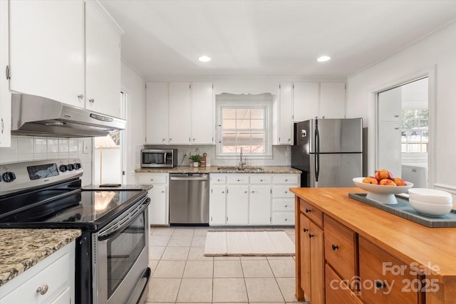 kitchen featuring light tile patterned flooring, a sink, under cabinet range hood, appliances with stainless steel finishes, and white cabinetry