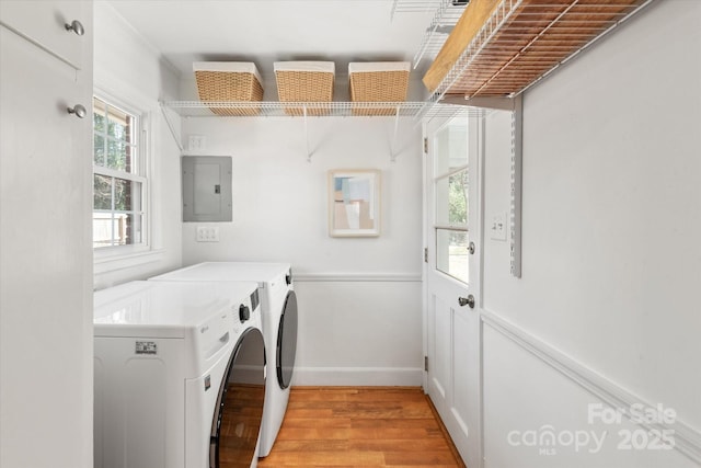 washroom with electric panel, separate washer and dryer, light wood finished floors, baseboards, and laundry area